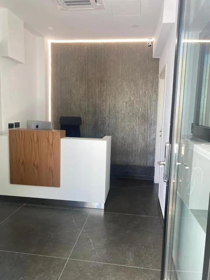 The small reception desk in oak and white against a dark textured wall
