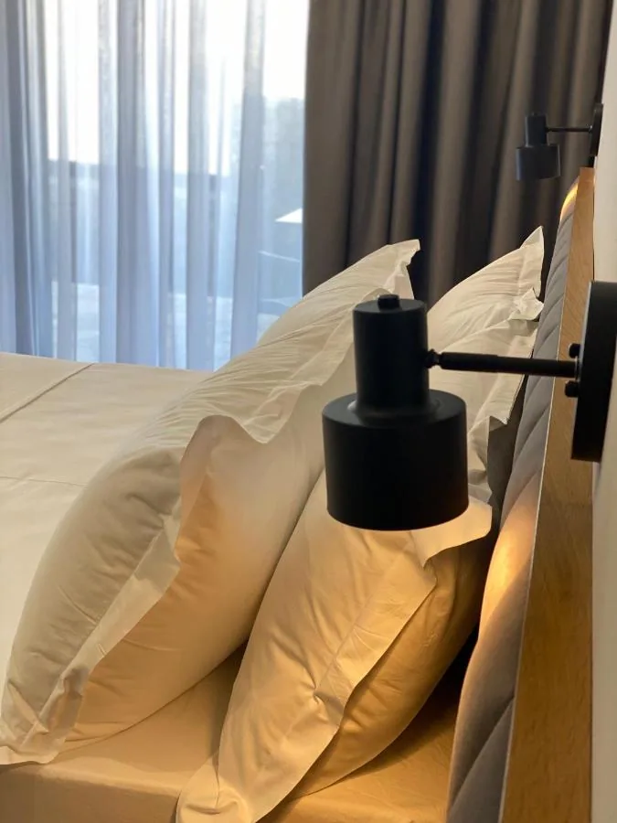 Pillows against a timber headboard with a black reading light