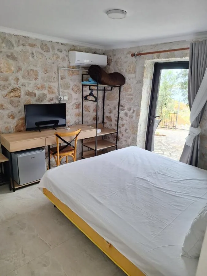 A ground-floor room with exposed rubble limestone walls, a desk and a glazed door onto a stone terrace