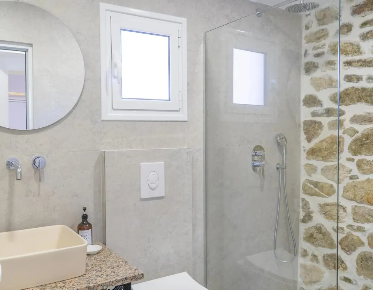 Walk-in shower built against the bare stone wall of the old house