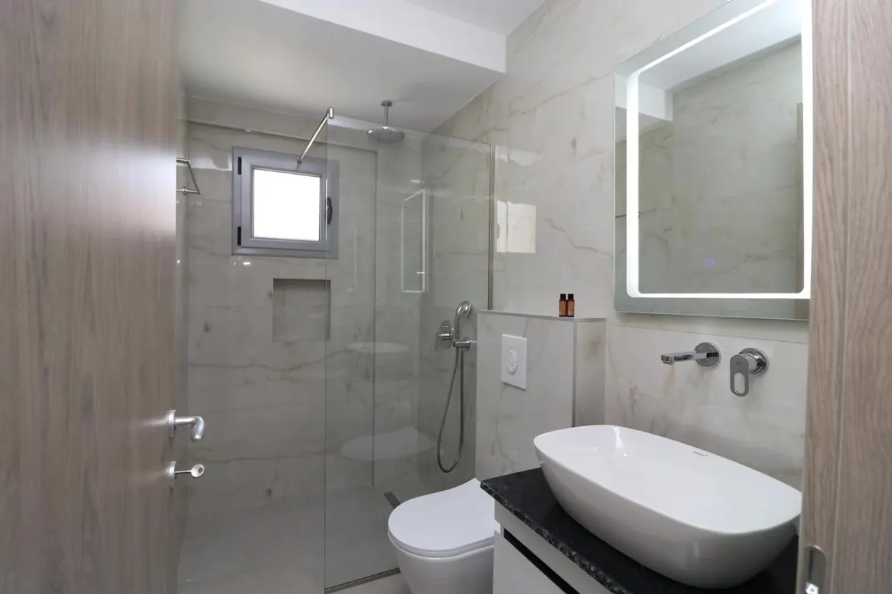 Bathroom with a walk-in glass shower and stone-tiled walls