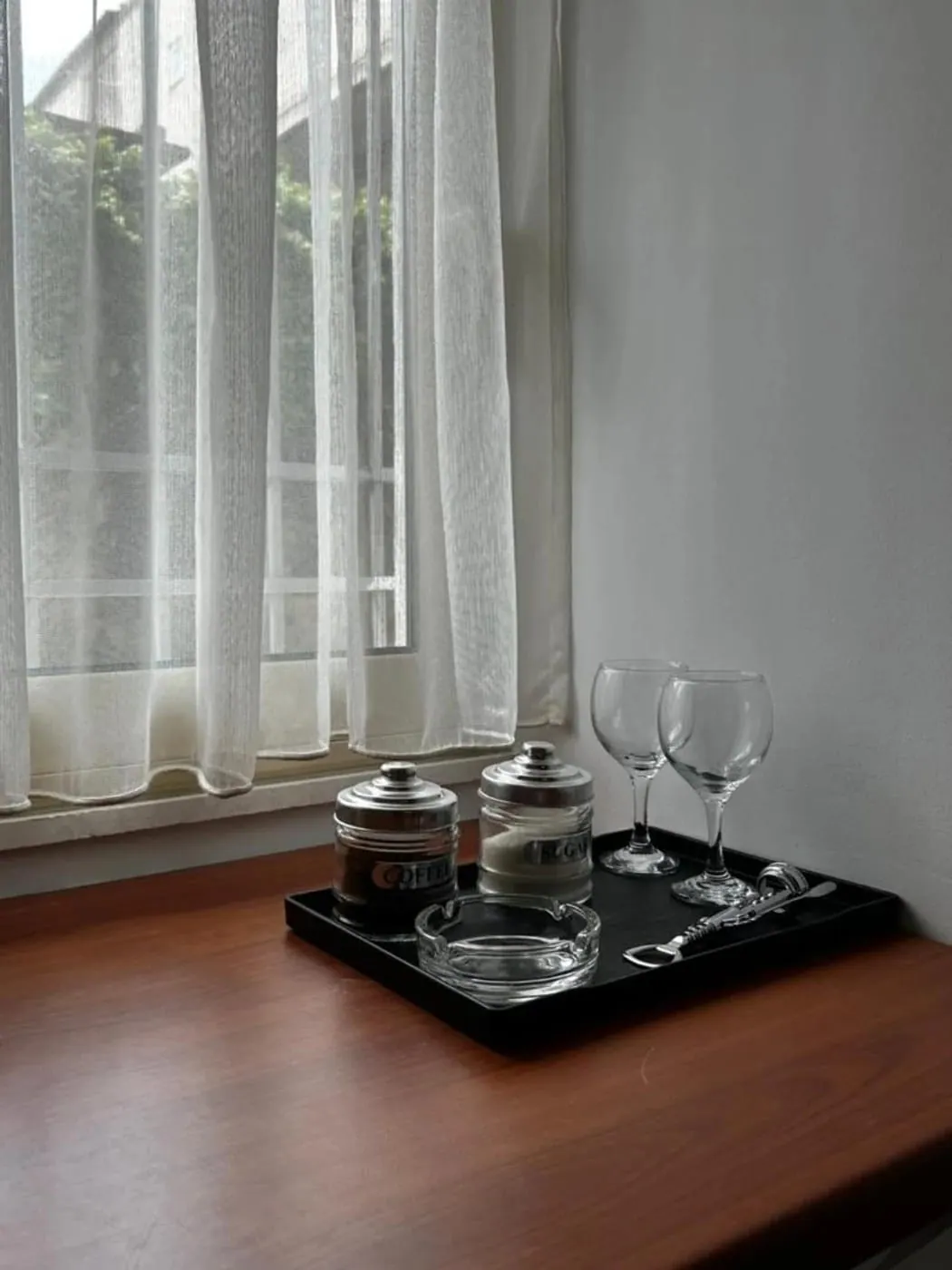 A tray of coffee, sugar and glasses on the desk beside the window