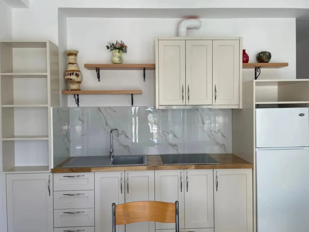 White apartment kitchen with a fridge, a hob and open shelves