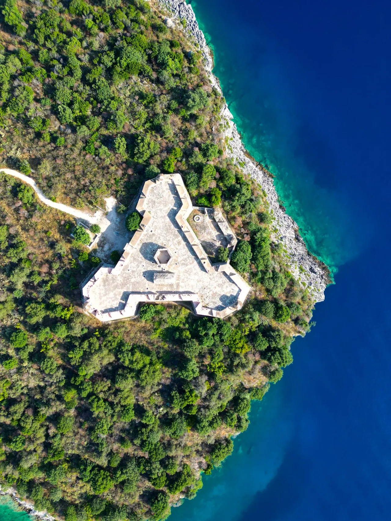 Porto Palermo Castle seen from the air on its wooded peninsula