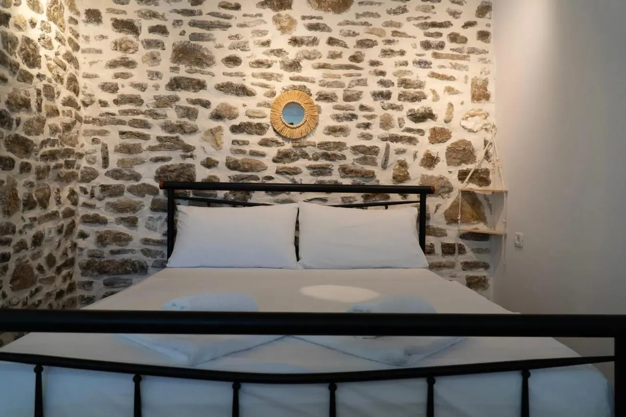 Double room with a black iron bed against an exposed stone wall