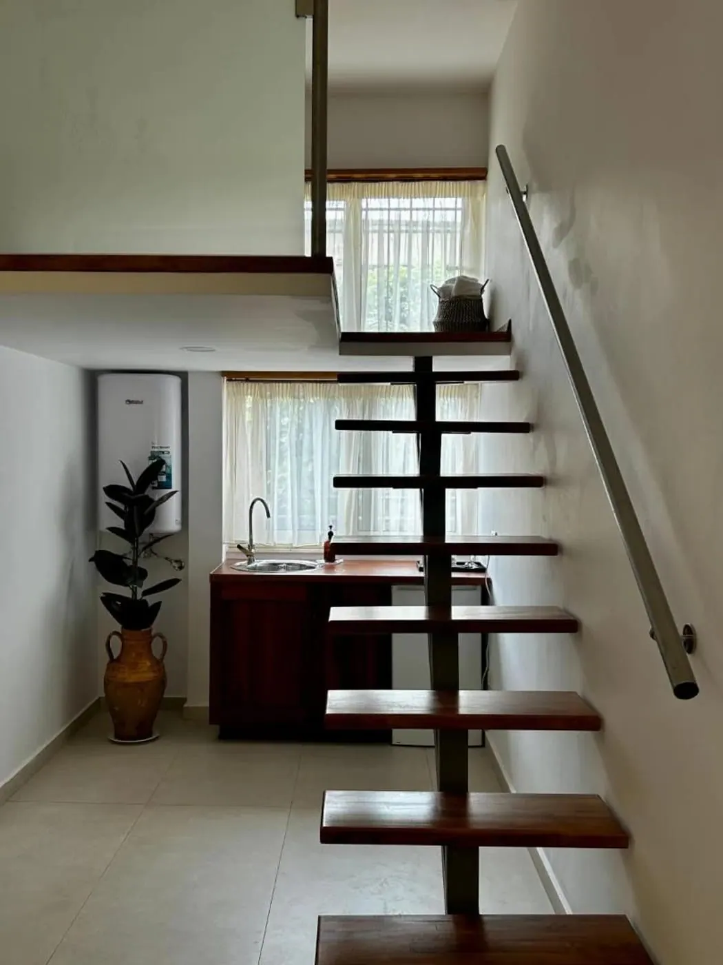 Open wooden stair to a mezzanine above a walnut kitchenette