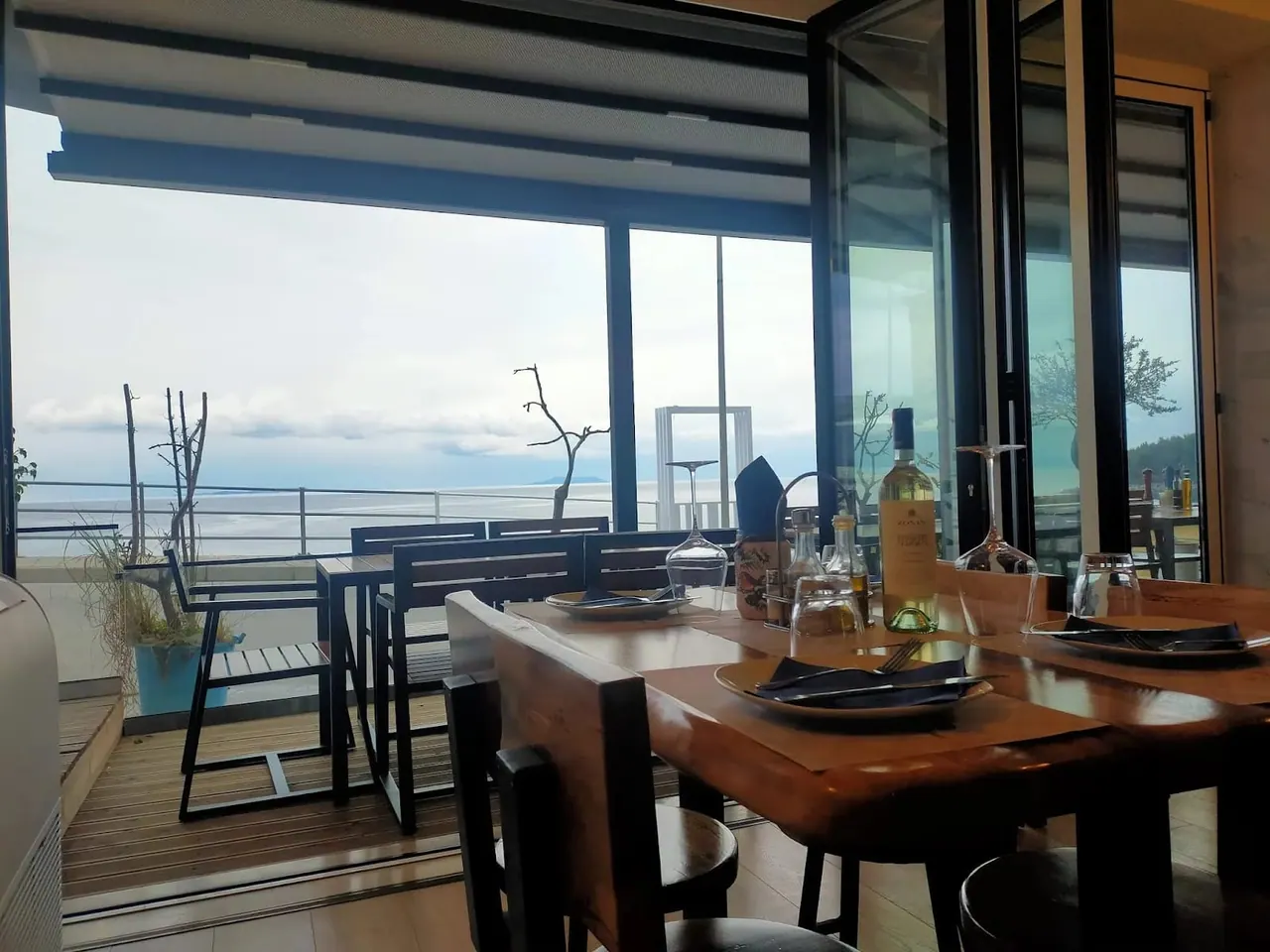 The restaurant's folding glass front opened onto a timber deck, with the bay and headland beyond