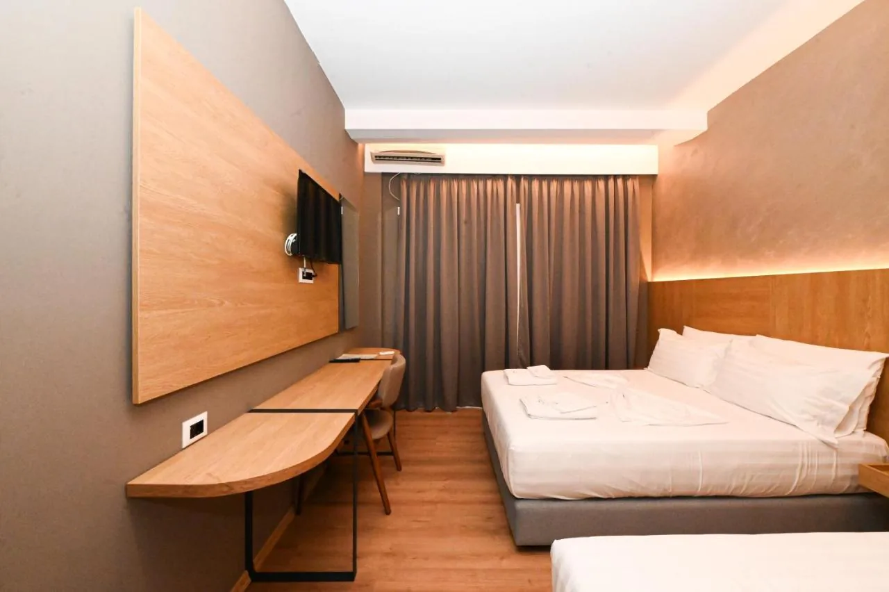 A refitted bedroom with grey walls, an oak headboard lit by a cove strip, a long desk and the curtains drawn.