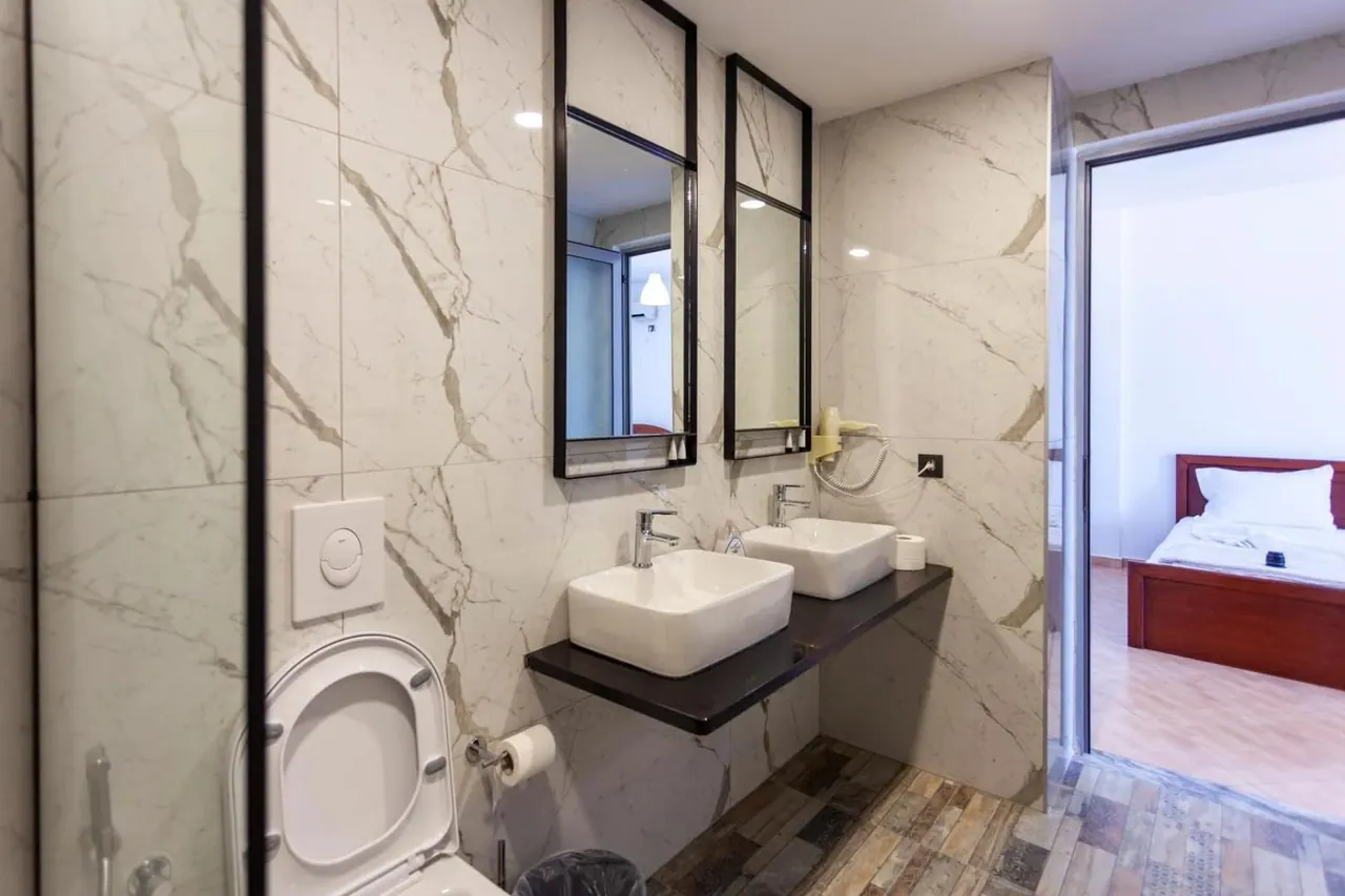 A marble bathroom with two square basins and black-framed mirrors