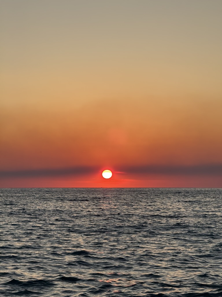 Sunset coastal view of Himara with orange sky over the Ionian Sea and mountain silhouettes
