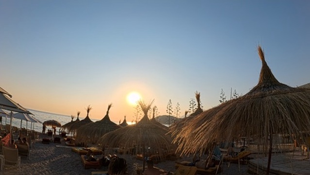 Beach bar straw umbrellas glowing at sunset on the Albanian Riviera coast