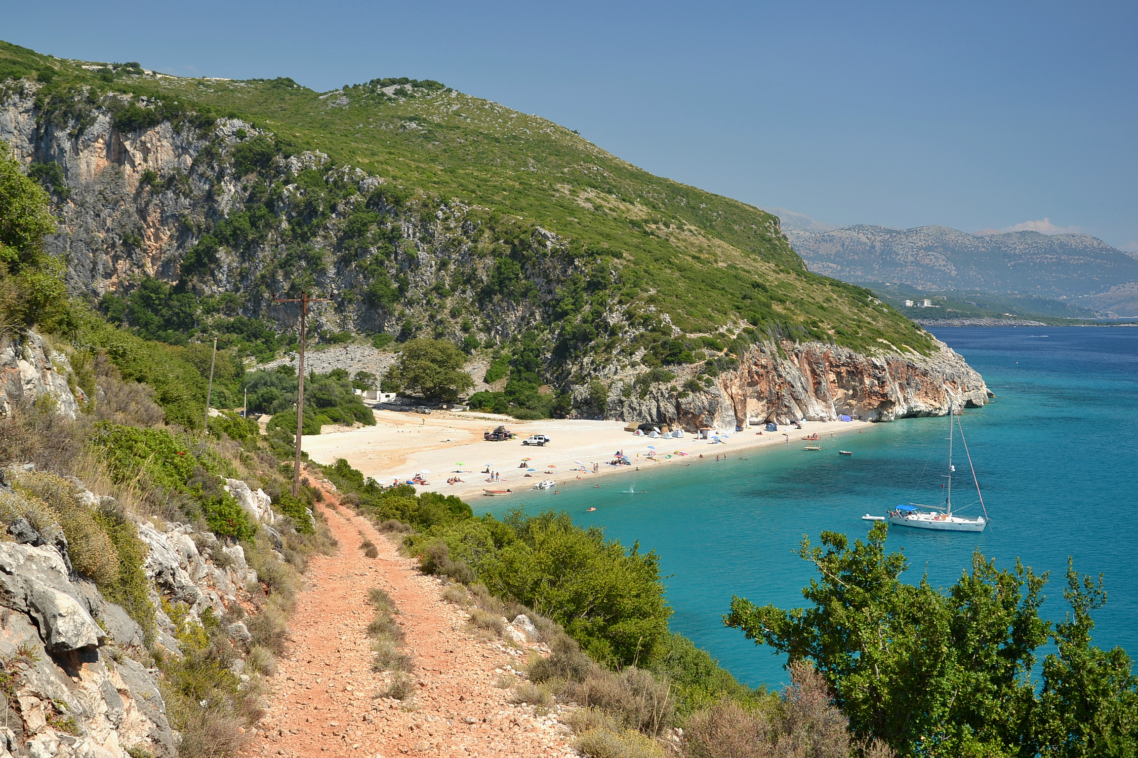 Gjipe Beach at the mouth of a canyon with clear blue water and dramatic cliff walls