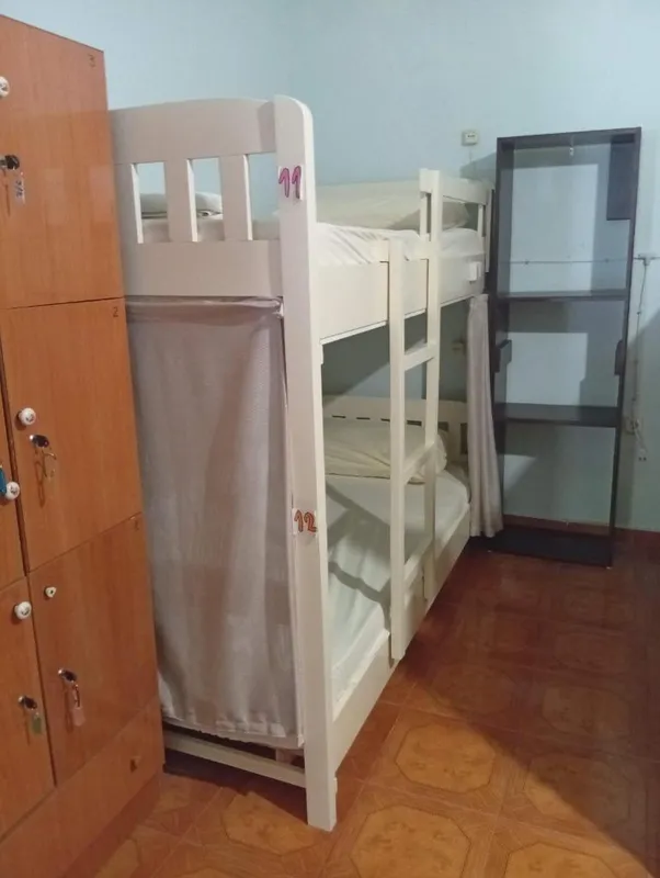 A bunk bed with hand-painted numbers 11 and 12 on the frame, privacy curtains drawn back, and wooden lockers with keys in the doors
