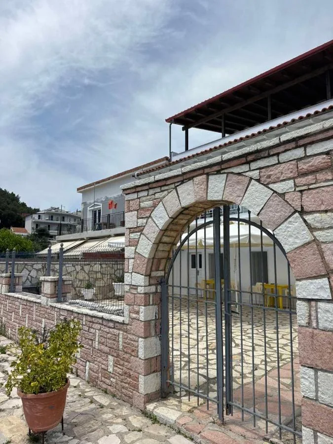 The round-headed stone gateway of AngelView Apartments with its two-leaf iron gate, seen from the lane, the building and its pergola behind