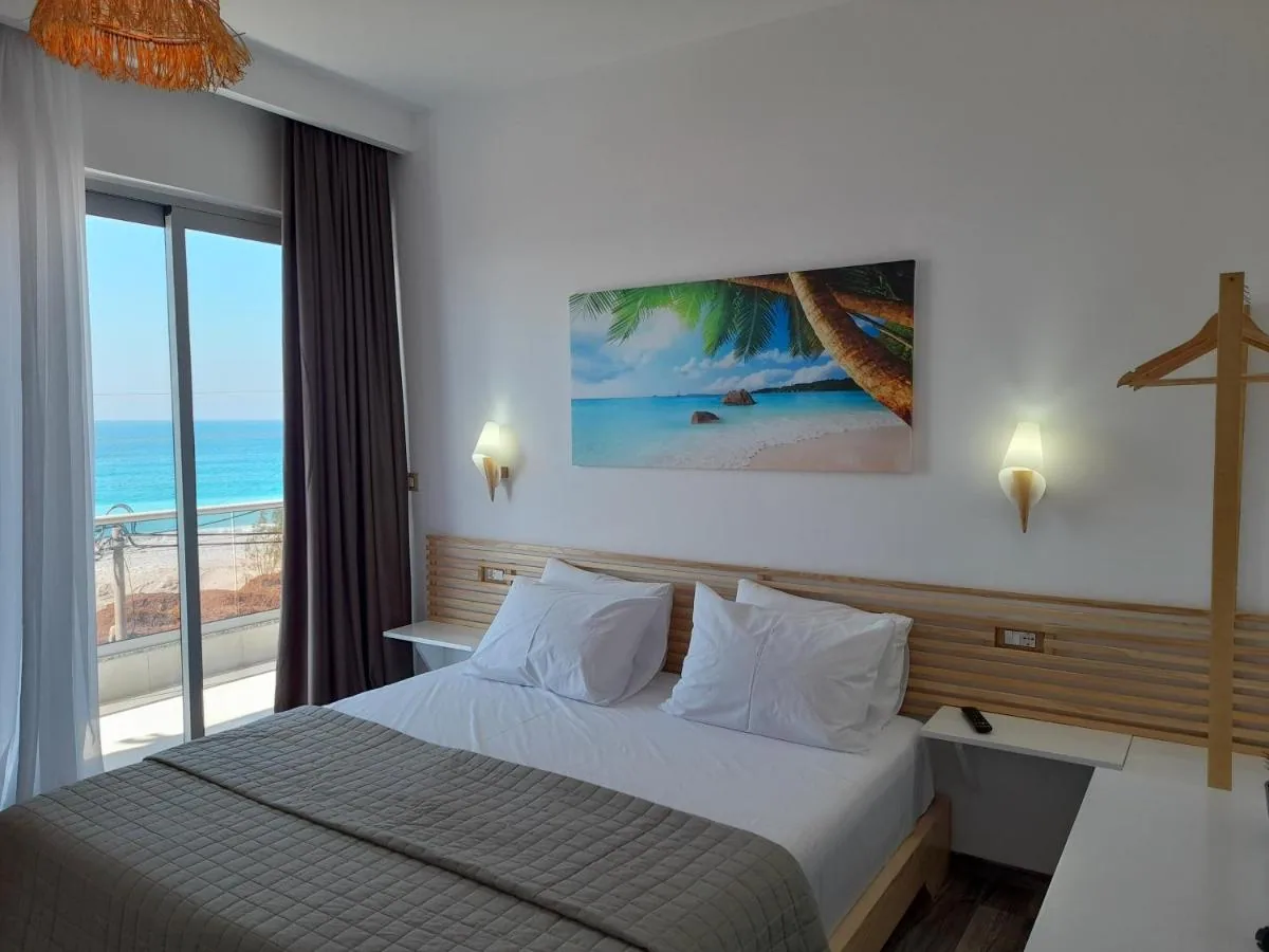 A double bed facing a sliding glass door that opens onto a balcony with the Ionian straight ahead.