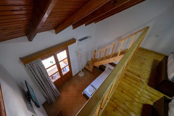 The mezzanine over the stair with a pine handrail and a boarded ceiling above two beds