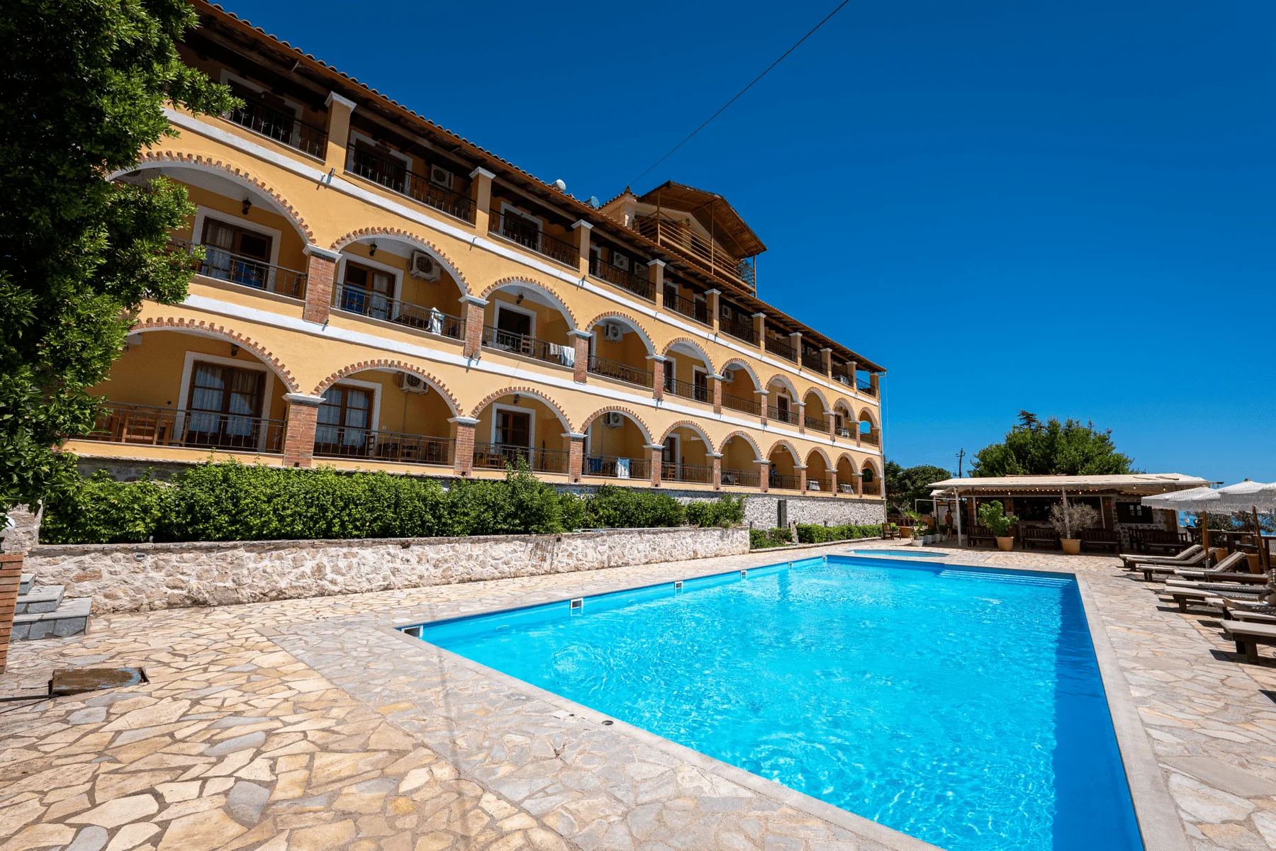 The full length of the building along the pool, two tiers of arches under a top storey on square piers and a red pantile roof