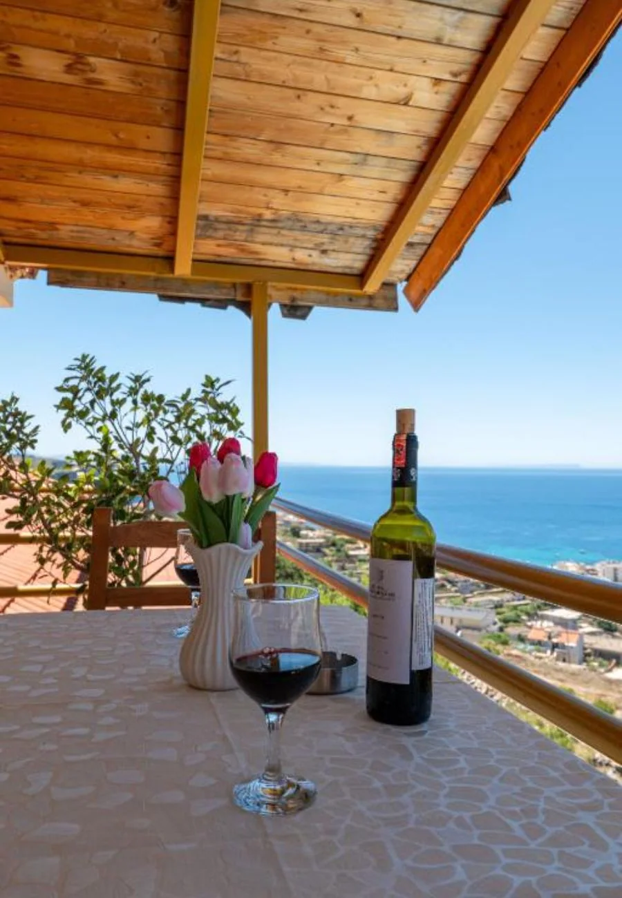 A terrace table under a pine-boarded canopy with the sea filling the frame beyond the balcony rail