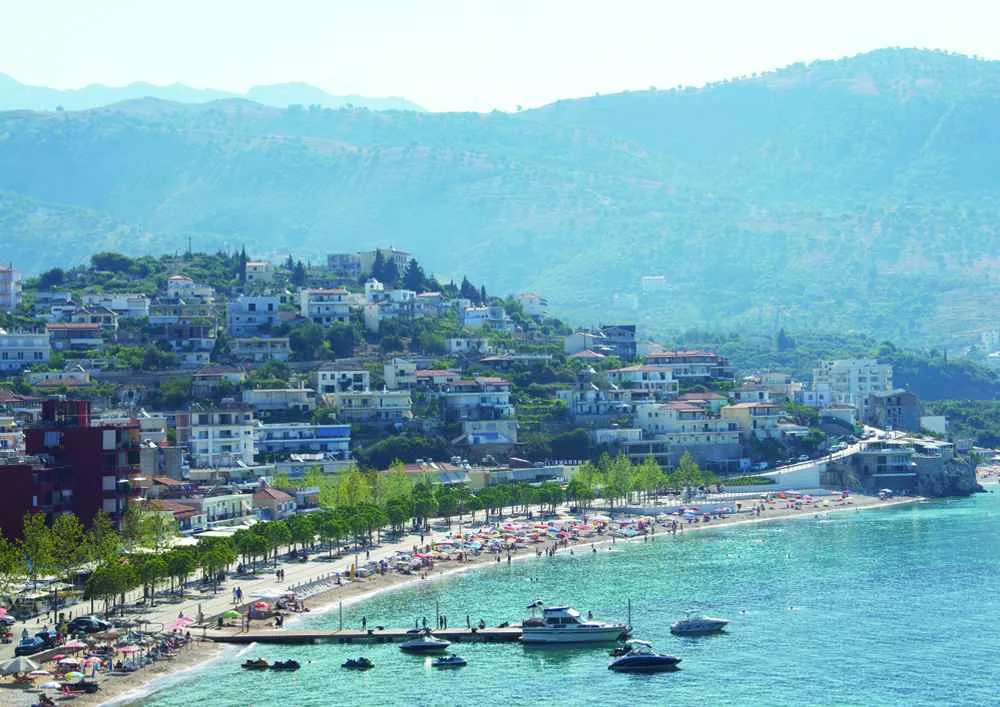 Spile beach curving away below the town, the tree-lined promenade behind it and the jetty running out into turquoise water