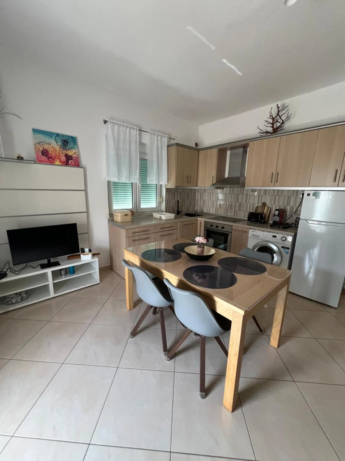 The kitchen wrapping two walls at the end of the living room, with a wooden dining table and four chairs at it