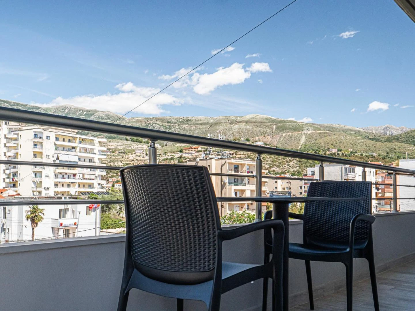 A balcony table looking over the rooftops of Himarë to the Ceraunian ridge