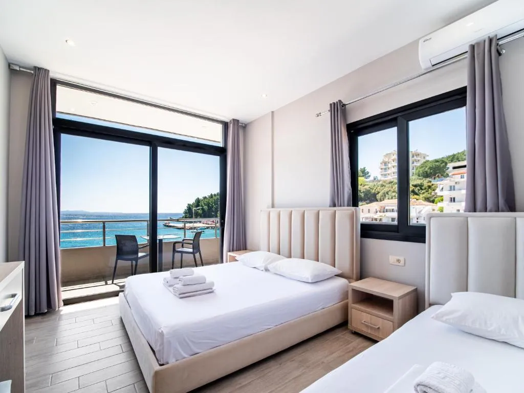 A room with a double bed and a second bed, a sea-facing balcony and a side window over the town