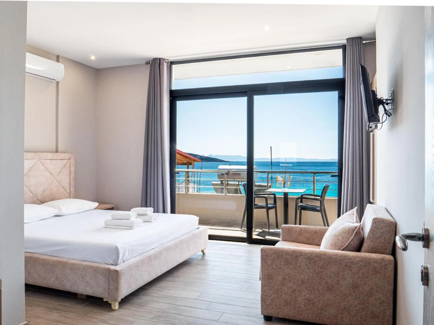 A double room with a sofa, air conditioning and sliding doors onto a sea-facing balcony