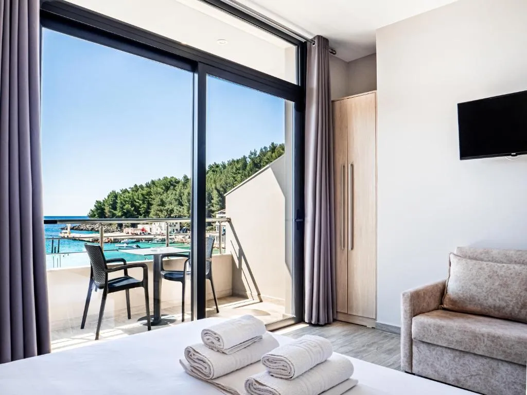 Sliding balcony doors in a guest room framing the harbour and the pine-covered headland
