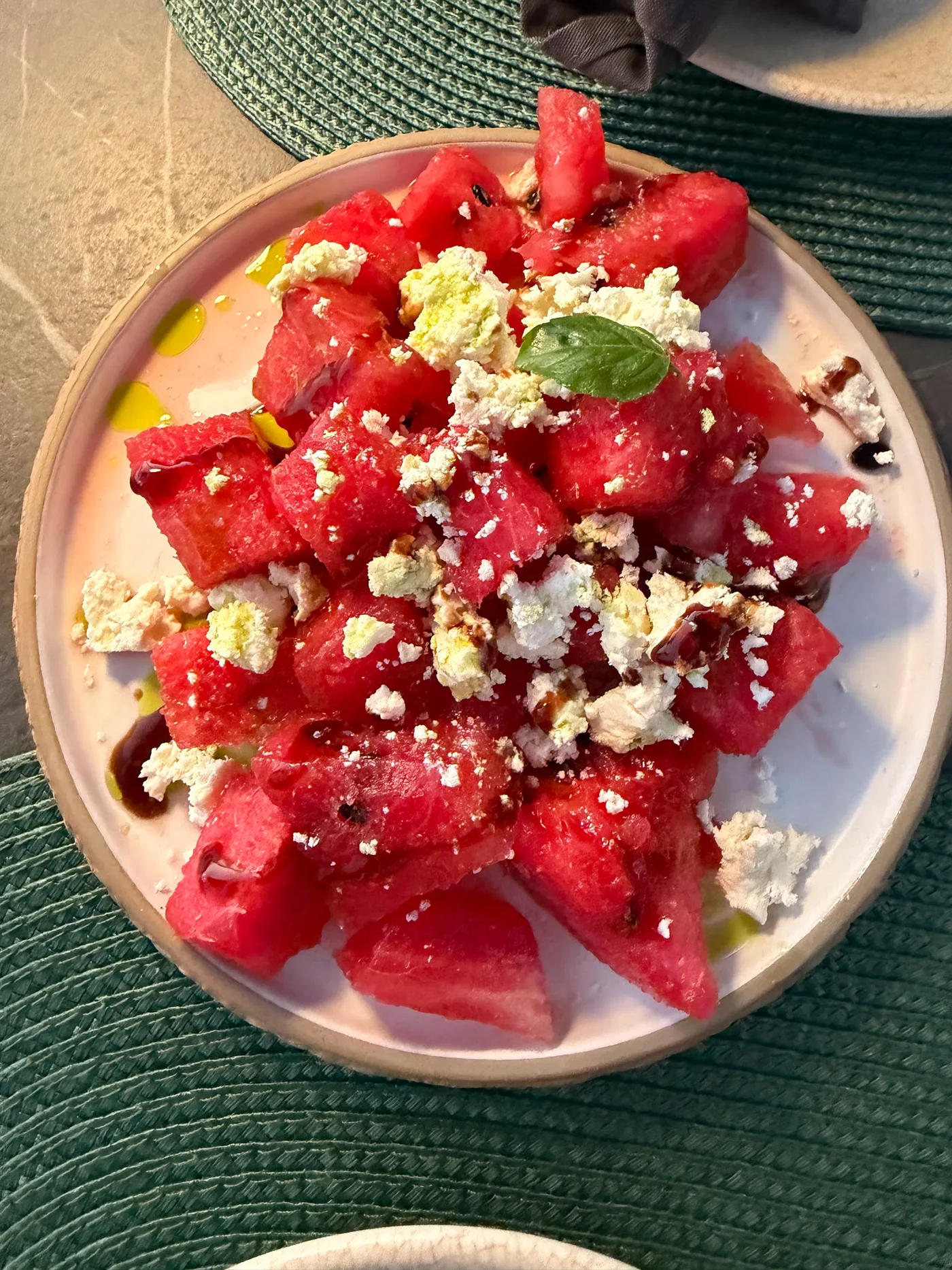 Watermelon and crumbled feta with a basil leaf and dark balsamic at Fig & Olive, Himarë