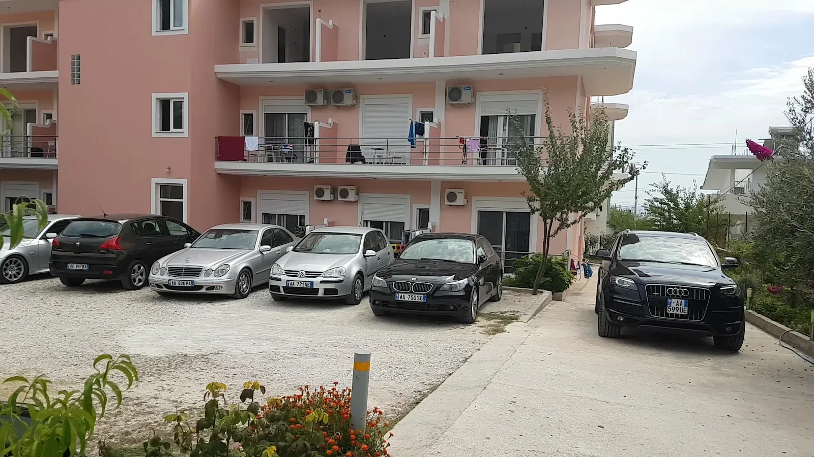 Cars parked on the hard standing in front of the hotel, balconies, roller shutters and wall air-conditioning units above