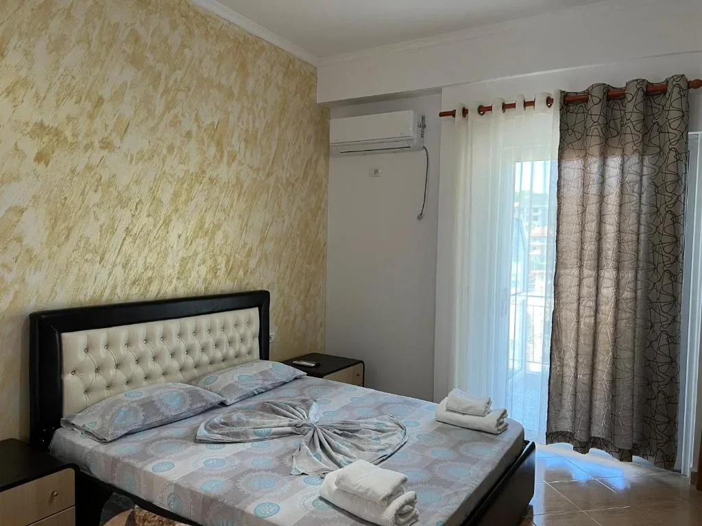 Standard Quadruple Room at Hotel Frida: a buttoned headboard against ochre plaster, with the balcony door alongside