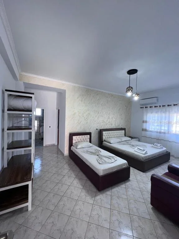 Family Suite at Hotel Frida: a single bed and a double bed against a textured wall, with an open shelf unit and a doorway through to the rest of the suite