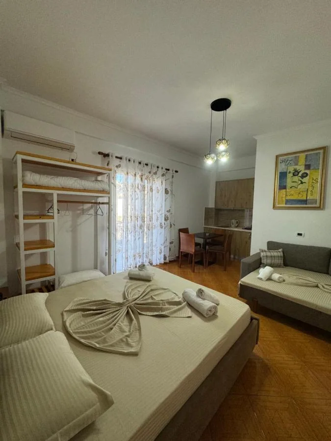 Triple Room at Hotel Frida: a full bed on parquet, a grey sofa bed against the right-hand wall and a kitchenette along the back wall