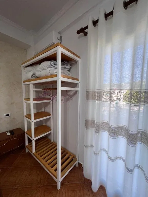 The open wardrobe and shelf tower beside the balcony curtain in a triple room at Hotel Frida