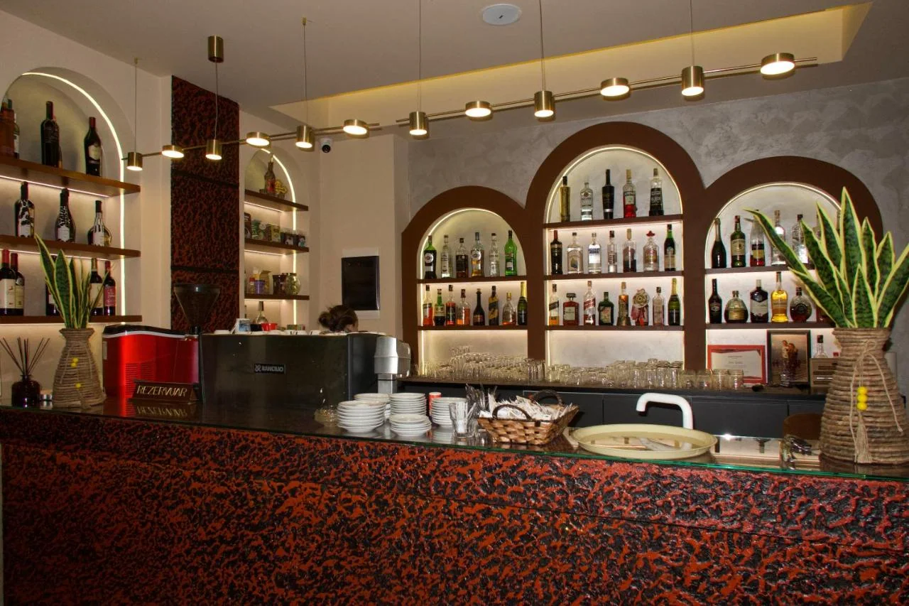 The bar at Hotel Frida: arched backlit niches of bottles above a counter faced in mottled red and black