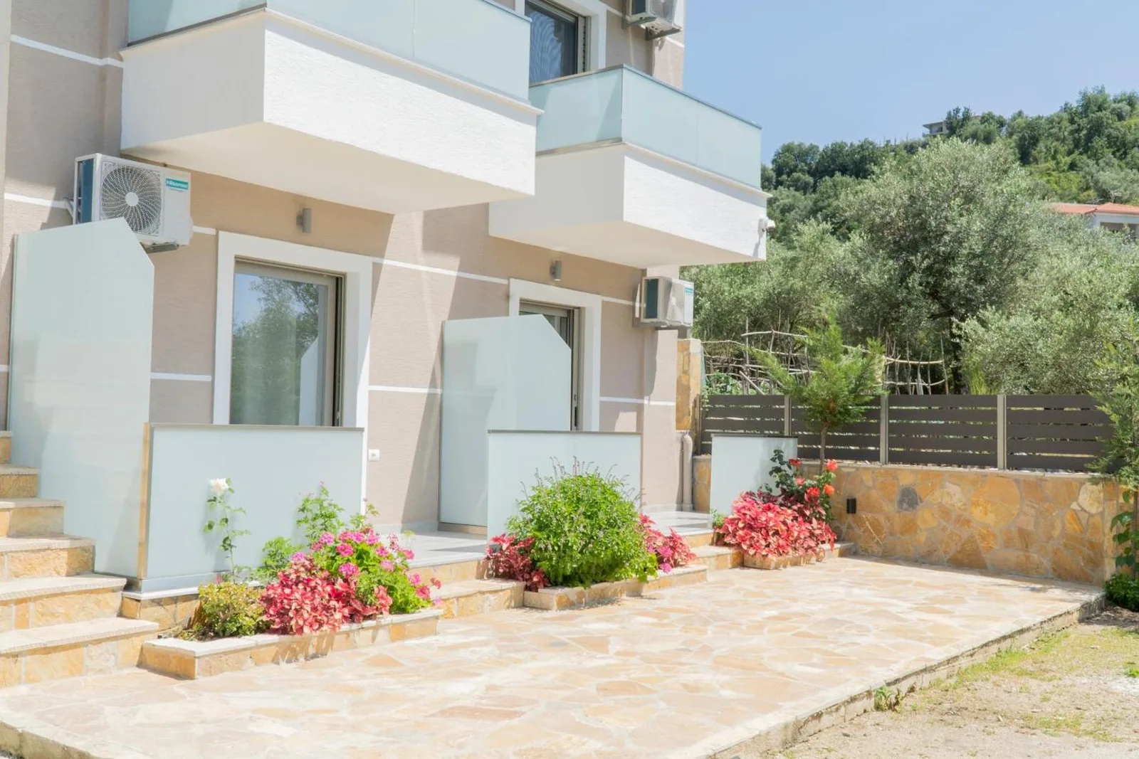 Ground-floor room terraces behind frosted glass screens, with flower beds