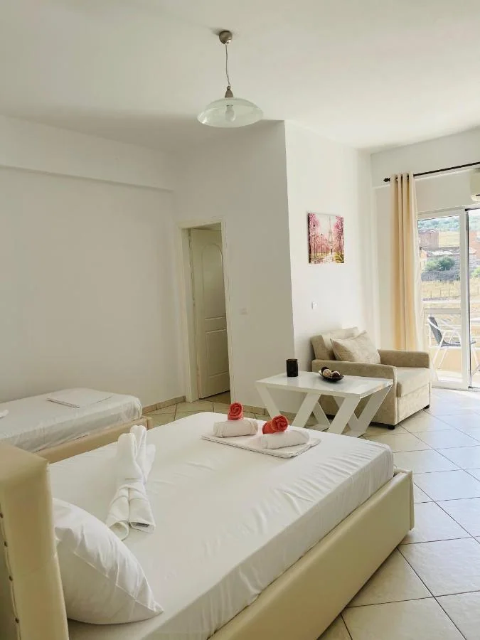 A double bed, a single bed, a sofa and a low table, with the balcony door open onto the hillside