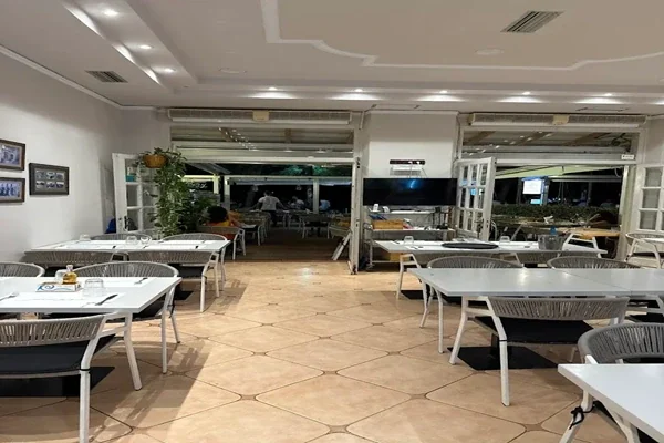The dining room behind the terrace, terracotta floor tiles and white tables, front folded open