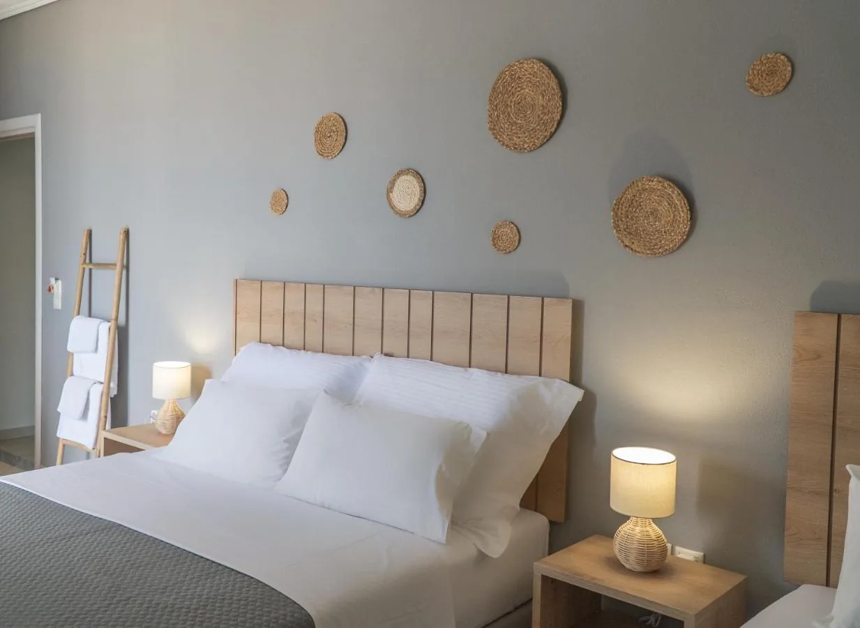 A double bed with a pale oak slatted headboard against a sage-grey wall hung with woven jute discs of different sizes
