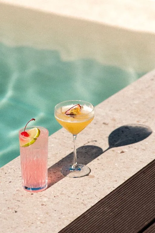 Two drinks on the pool coping in the sun