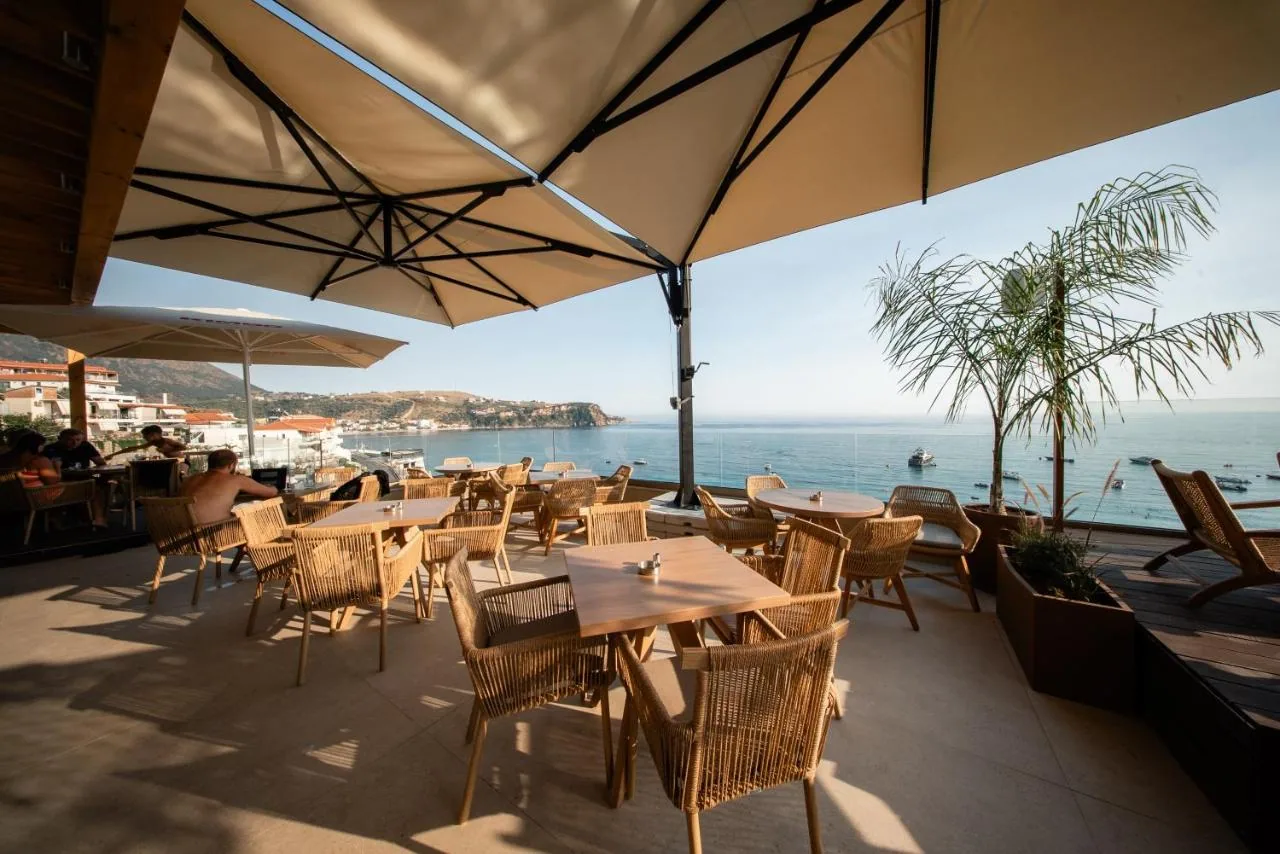 Tables under a parasol on the roof terrace, Himarë bay beyond