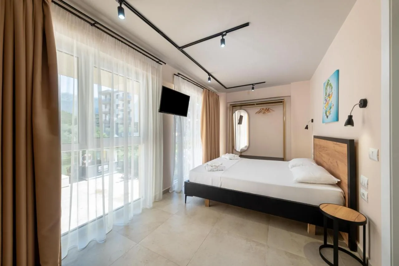 A double room with an oak headboard, track lighting and a balcony behind sheer curtains