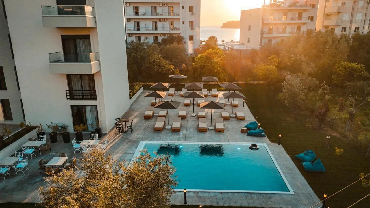 The Blue Wave Hotel's pool, sun terrace and lawn from above at sunset, with the Ionian beyond the tree line