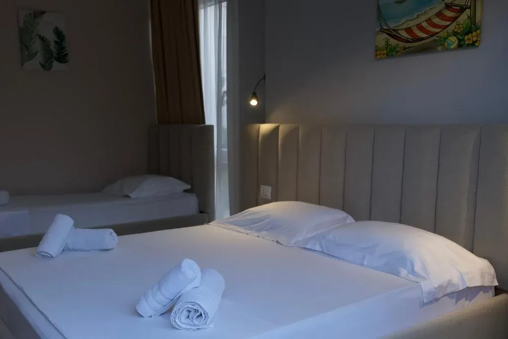 A single bed and a double bed with ribbed cream headboards beside a glazed balcony door