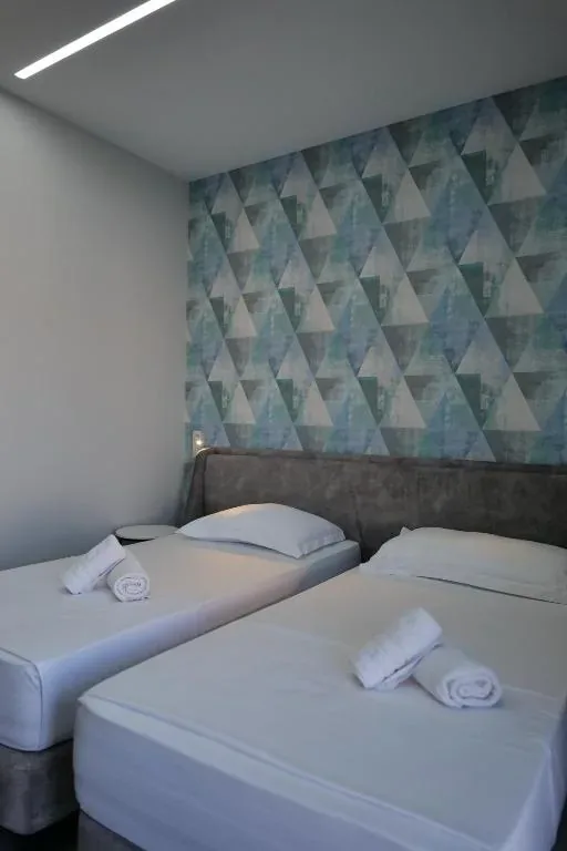 Two beds side by side under a teal and grey triangle feature wall