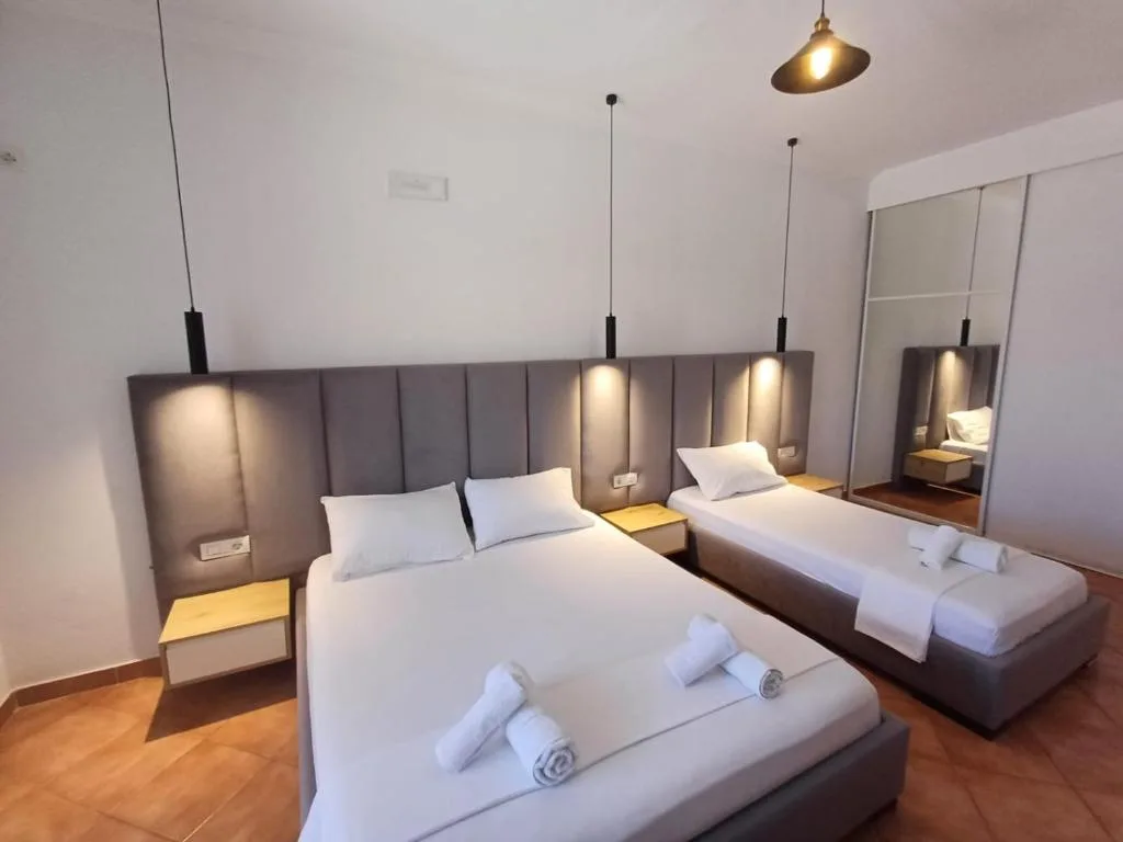 A deluxe triple room at Velco BB Himara with a double bed and a single bed under a padded headboard
