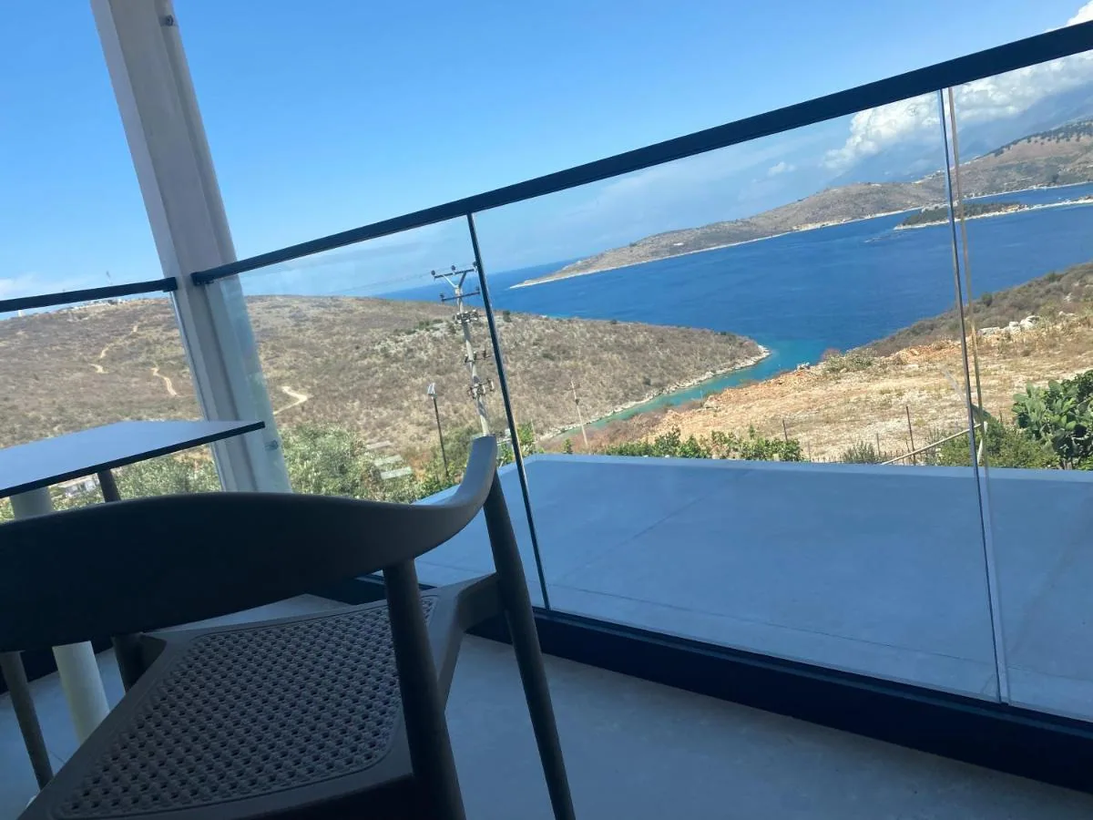 A balcony table and chair with the inlet and headland of Porto Palermo below