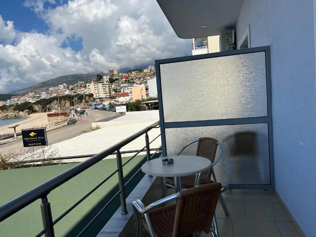 The view north along the coast from a balcony at Hotel Prinos: the road below, the beach, and the hillside town of Himarë rising beyond