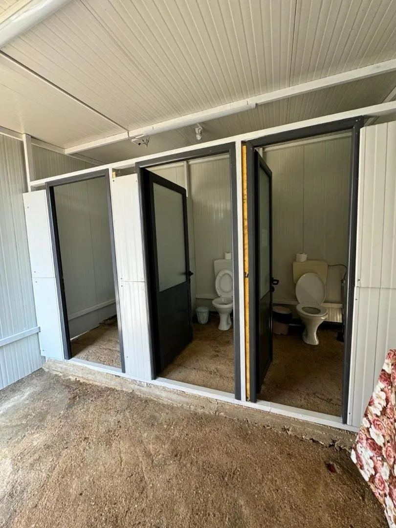 The cubicle block at Olive Camping — full-height WC cubicles with dark-framed doors under a covered walkway
