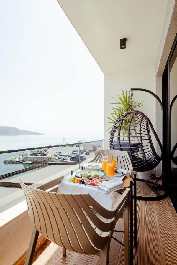 Breakfast laid on a balcony table with a hanging egg chair, above a quay with parked lorries and the sea beyond